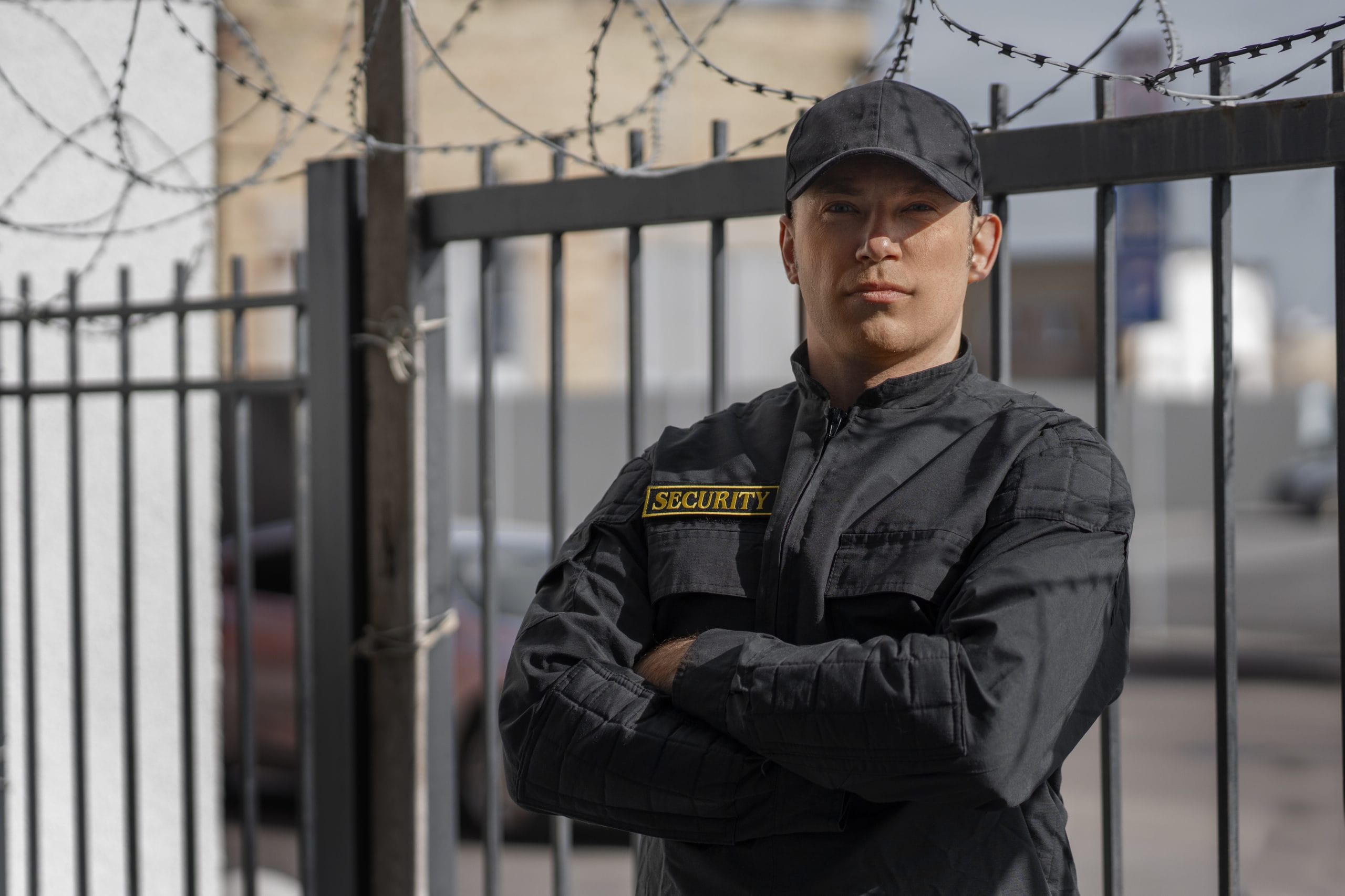 portrait-male-security-guard-with-barbed-wire-fence-scaled